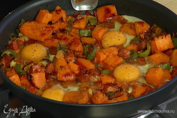 Яйца разбить в сковороду с колбасой и овощами, посолить, поперчить и запекать в разогретой духовке 3–4 минуты.