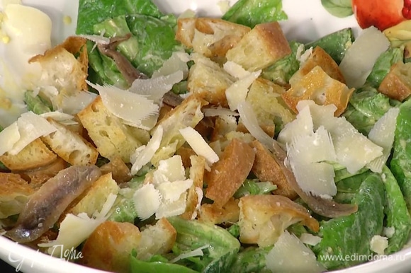 Листья салата смешать с заправкой, добавить гренки, анчоусы, сыр, все перемешать.