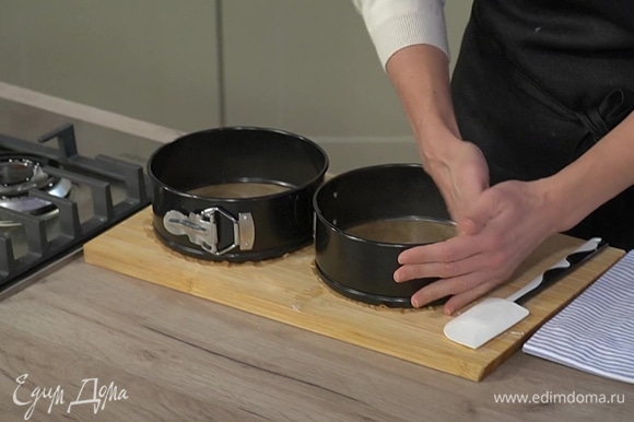 Две круглые разъемные формы застелить бумагой для выпечки, смазать оставшимся сливочным маслом и равномерно выложить тесто.