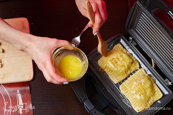 Разогрейте гриль, мультипекарь или сковороду. Выложите заготовки. Смажьте верх желтком.