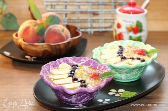 Разлейте фруктовое пюре по мискам. Украсьте смузи ягодами, фруктами, кокосовой стружкой, обжаренными и измельченными орешками и листиком мяты.