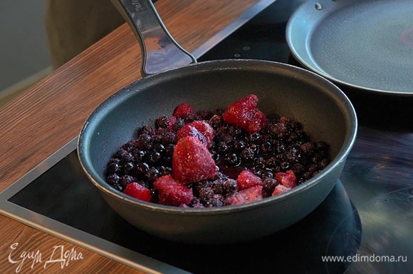 В отдельную сковороду выложите замороженные ягоды, добавьте сахар и воду. Уваривайте до загустения на среднем огне.
