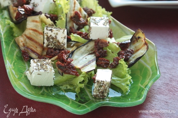 Выложите листья салата, на них распределите баклажаны, вяленые томаты и сыр, сбрызните салат заправкой и наслаждайтесь!