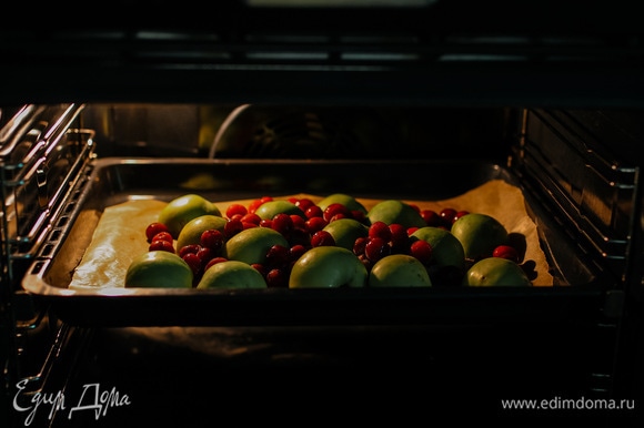 Яблоки разрезать пополам и выложить на противень кожурой вверх, добавить вишню и запекать при 180°C 25–30 минут.