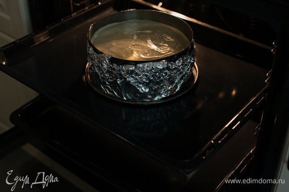 В глубокий противень влить горячую воду и поставить на нижний ярус духовки. Чизкейк выпекать на противне посередине при 115°C в течение 90–120 минут. Готовность определяется слегка дрожащей серединой.