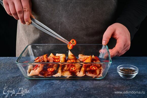 Добавьте нарезанный кружочками перец чили и черный перец по вкусу. Накройте рыбу пленкой и поставьте мариноваться на 2 часа.