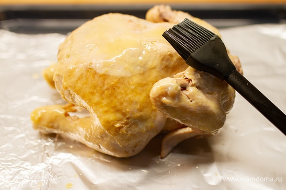 Курицу выложить на тарелку, дать немного остыть, затем переложить в глубокий противень, застеленный пищевой фольгой. Сливочное масло (20 г) растопить и с помощью кисточки смазать тушку. Посолить и поместить в духовку, нагретую до 190°C, на 20 минут.
