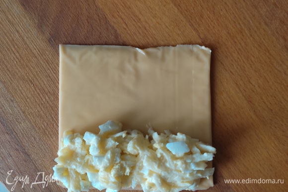 На пластинку сыра выкладываем на один край начинку и аккуратно сворачиваем в трубочку. Начинки должно быть столько, чтобы пластинка соединилась краями.