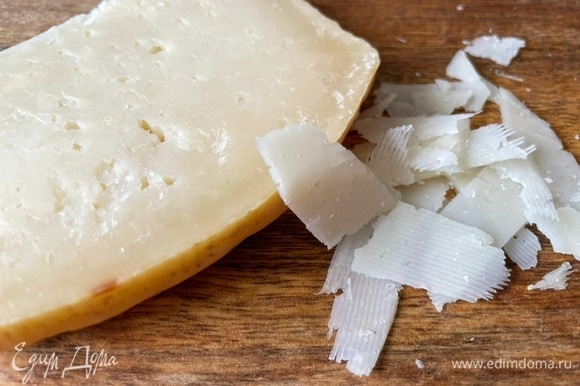 Сыр натрите слайсами с помощью овощерезки.