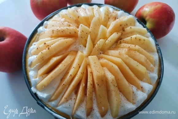 Поверх крема выложить дольки яблок. Посыпать корицей и отправить пирог в предварительно разогретую духовку до 180°C на 40–45 минут.