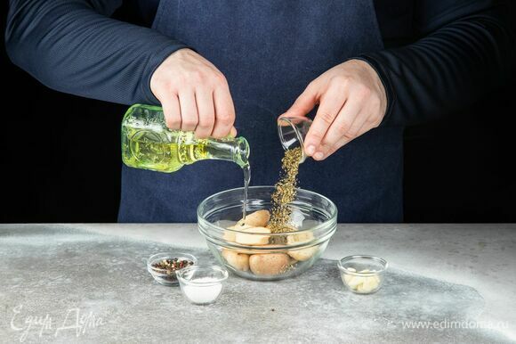 В глубокую чашу выложите разрезанный на половинки картофель, полейте оливковым маслом, добавьте рубленый чеснок, орегано, тимьян, соль и перец. Запекайте в разогретой до 180°C духовке около 20 минут.