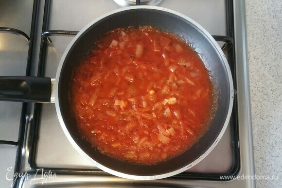 После этого для приготовления соуса нужно снова смазать сковороду сливочным маслом. Выложить измельченный репчатый лук, протертые помидоры и сушеный базилик. Перемешать. И на маленьком огне, помешивая, готовить соус к пицце около 10–15 минут (до мягкости лука).