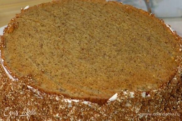 Один корж смазать кремом и накрыть вторым коржом, бока пирога смазать оставшимся кремом, посыпать бисквитной крошкой и прижать ее руками.