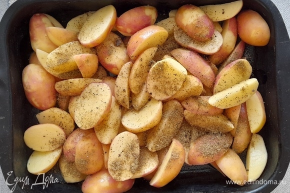 Полейте картофель растительным маслом, посыпьте хмели-сунели и черным молотым перцем, перемешайте. Дайте постоять 10 минут. Затем поставьте форму с картофелем в духовку, разогретую до 200°C.