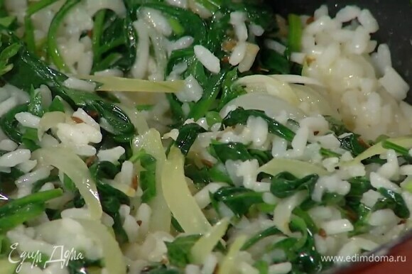 Выложить к луку со шпинатом готовый рис, влить горячий бульон, посолить, добавить нарезанную зелень и все перемешать.