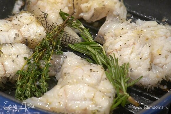Стейки полить оливковым маслом, посолить, поперчить с двух сторон и обжаривать на разогретой сковороде-гриль с каждой стороны по 2 минуты, в конце выложить к рыбе веточки розмарина и тимьяна.