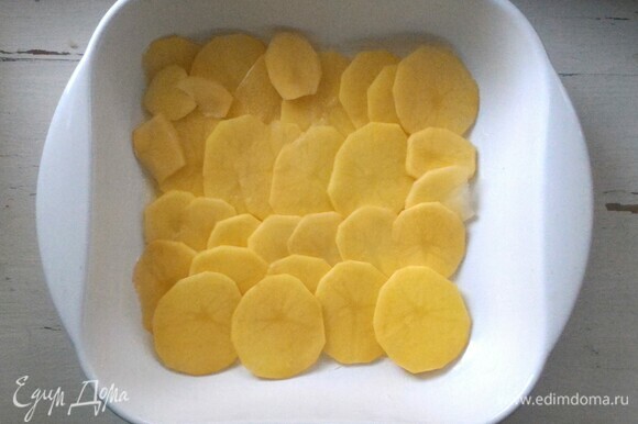 Форму для запекания смазать кусочком холодного сливочного масла. Выложить кружочки картофеля немного внахлест друг на друга.
