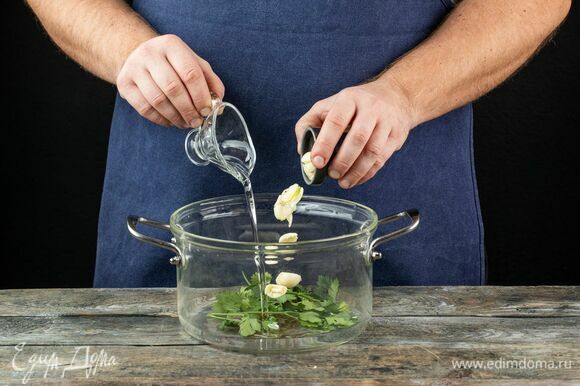 В разогретую кастрюлю налейте оливковое масло, добавьте зубчики чеснока, раздавленные ножом, и пучок петрушки.