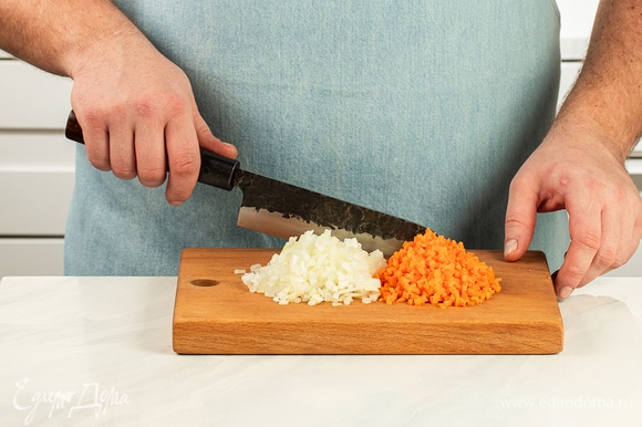 Мелко нарежьте лук и морковь. В сковороде с высокими бортами нагрейте растительное масло и обжарьте овощи до золотистого цвета.