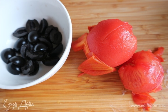Приготовить помидоры. Нанести крестообразные насечки у плодоножки. На 30–40 секунд поместить в кипяток, снять шкурку, нарезать на кубики. Маслины нарезать на половинки.