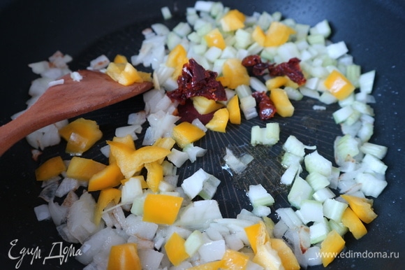 Разогреть сковороду с оливковым маслом и раздавленным с помощью ножа зубчиком чеснока, через некоторое время чеснок вынуть из сковороды, поместить лук, обжарить слегка (до прозрачности). Через несколько минут добавить сельдерей, болгарский перец, вяленые помидоры.