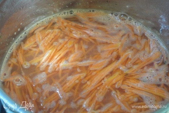 Морковь натрите на терке. В кастрюле с толстым дном разогрейте растительное масло и обжарьте в нем морковь. Добавьте рубленый чеснок, перемешайте и залейте горячим бульоном или водой.