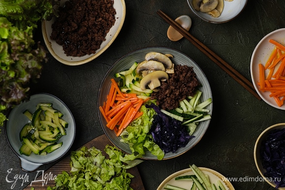 Сверху на рисовую подушку выложите припущенные овощи, грибы, фарш, а также нарезку из свежего огурца и салат.