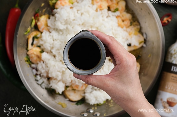 Положите рис, перемешайте, влейте соевый соус и прогрейте все вместе в течение 2–3 минут.