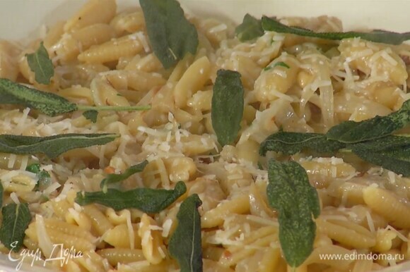 Готовые макароны посыпать фундуком и петрушкой, выложить в глубокое блюдо, посыпать оставшимся пармезаном и украсить обжаренными листьями шалфея.