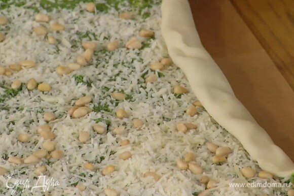 Размороженное тесто тонко раскатать, равномерно смазать соусом песто, посыпать сыром, орехами и свернуть по длинной стороне в рулет.